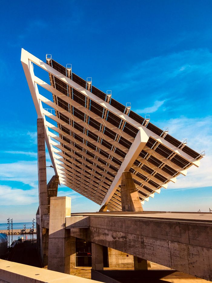 Photograph of a large solar panel installation set against a clear blue sky, highlighting renewable energy.